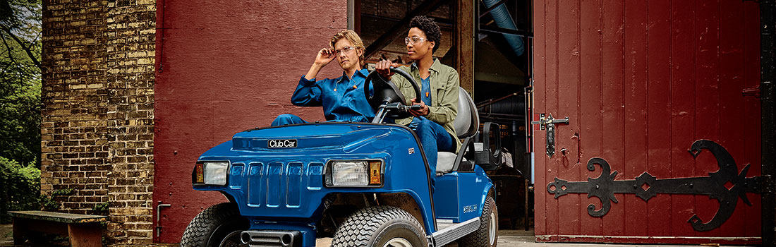 브랜드 Club Car의 파란색 골프카에 탄 두 사람의 모습